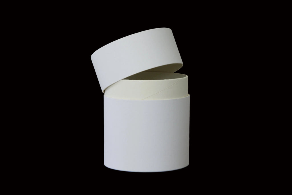 white cylindrical containers stacked on a wooden surface with a light gray background