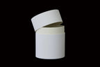 white cylindrical containers stacked on a wooden surface with a light gray background