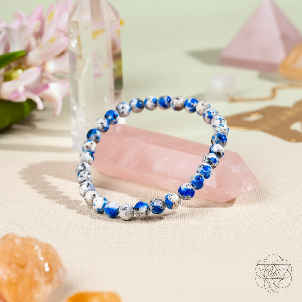 Beaded bracelet with blue and silver beads on a pink surface with decorative elements.