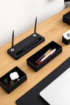 Black desk organizers with stationery on a wooden surface