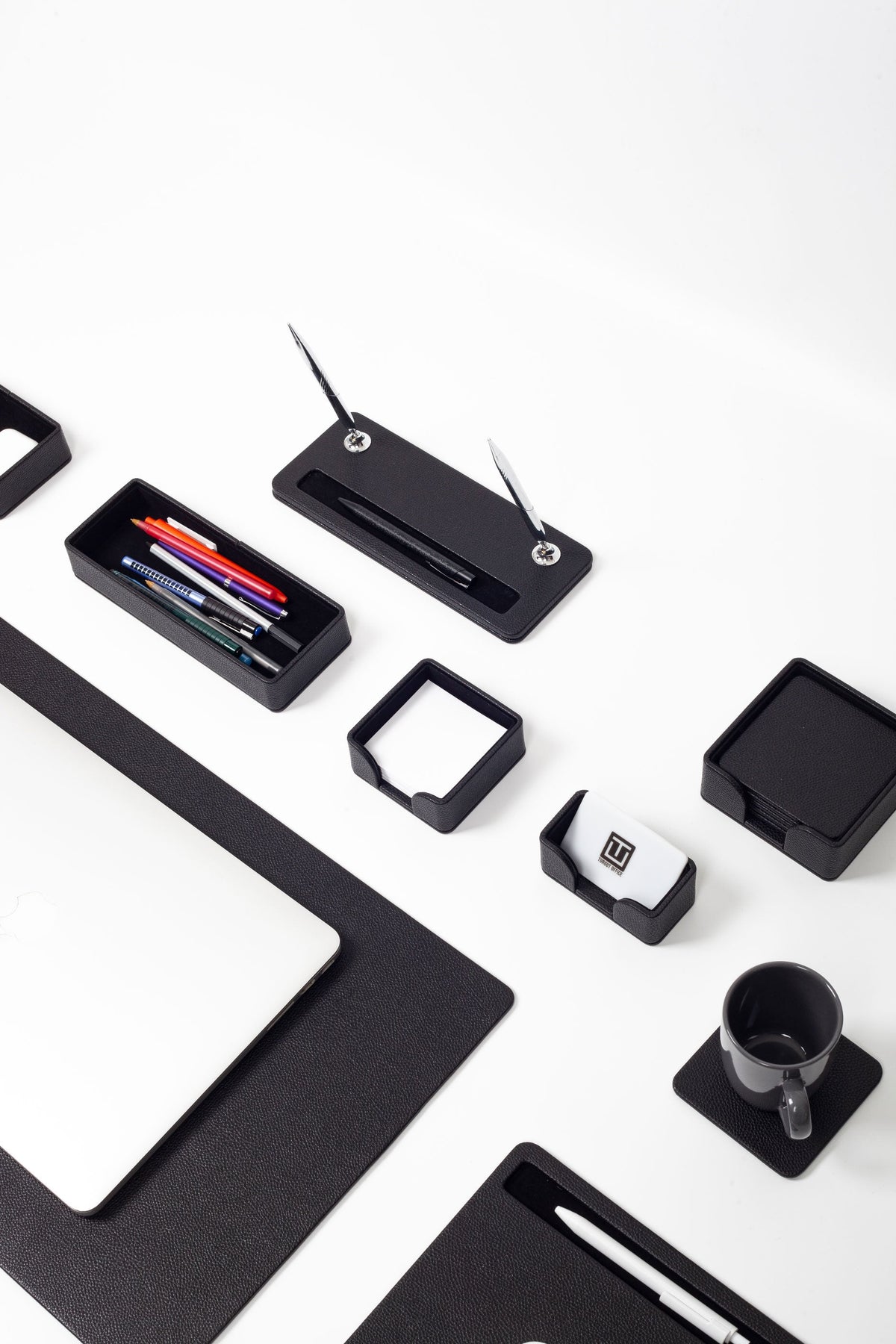 Black office accessories including a phone stand, pen holder, and mug
