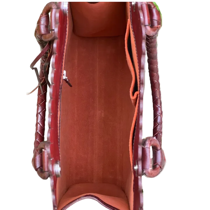Close-up of a brown leather bag with braided handles on a white background