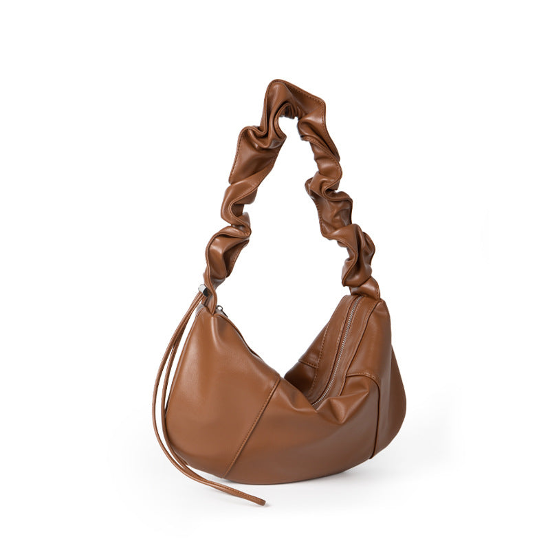 Brown leather handbag with twisted handle on a white background