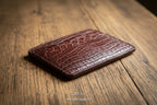 Brown leather cardholder with crocodile texture on a white background
