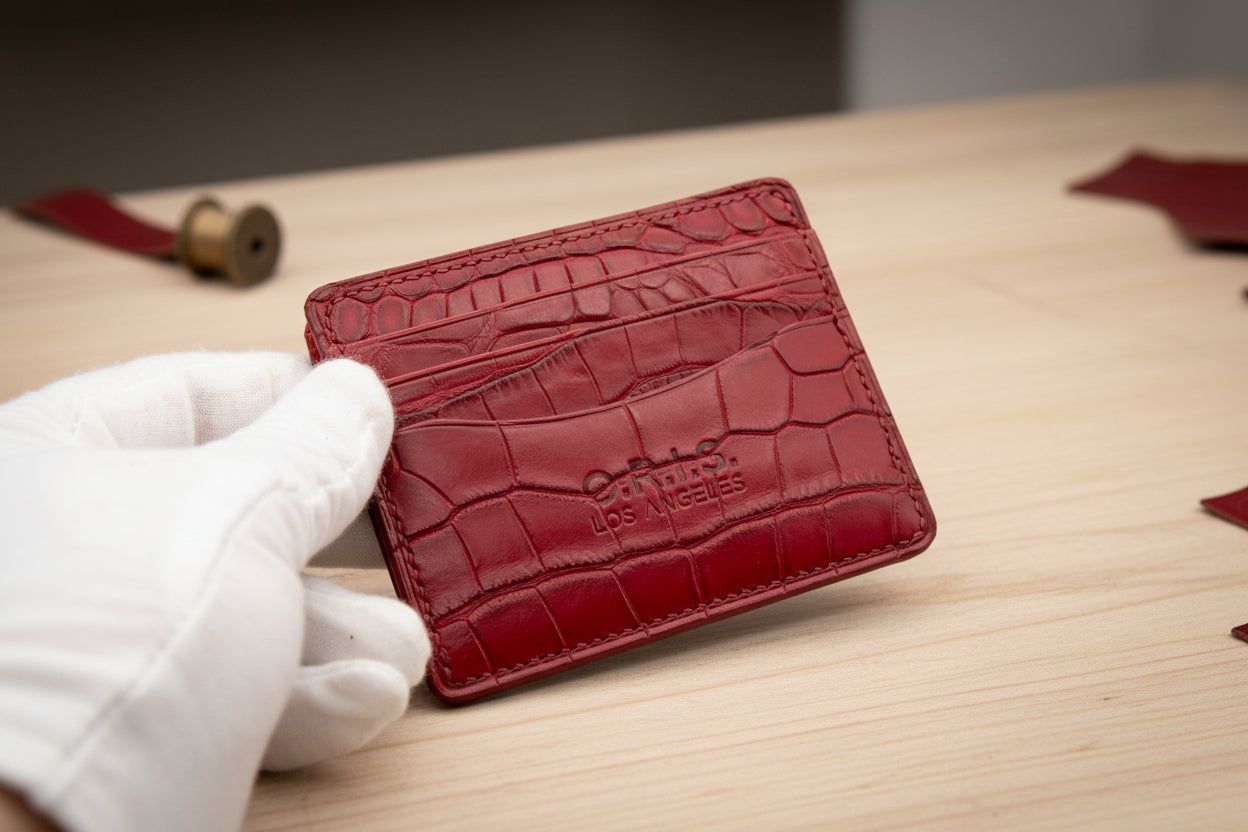Red crocodile-patterned wallet held by a gloved hand