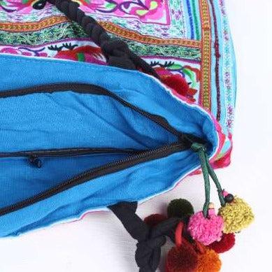 Blue drawstring bag with colorful pom-pom tassels on a white background