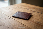 Brown leather cardholder with crocodile texture on a light gray background, featuring the brand 'ORIS'.