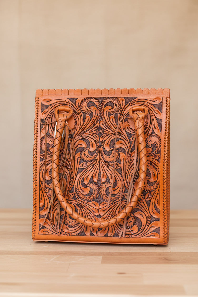Orange leather bag with intricate patterns on a wooden surface