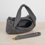 Grey handbag with gold accents on a light grey leather