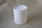 White cylindrical container with a lid on a beige fabric background