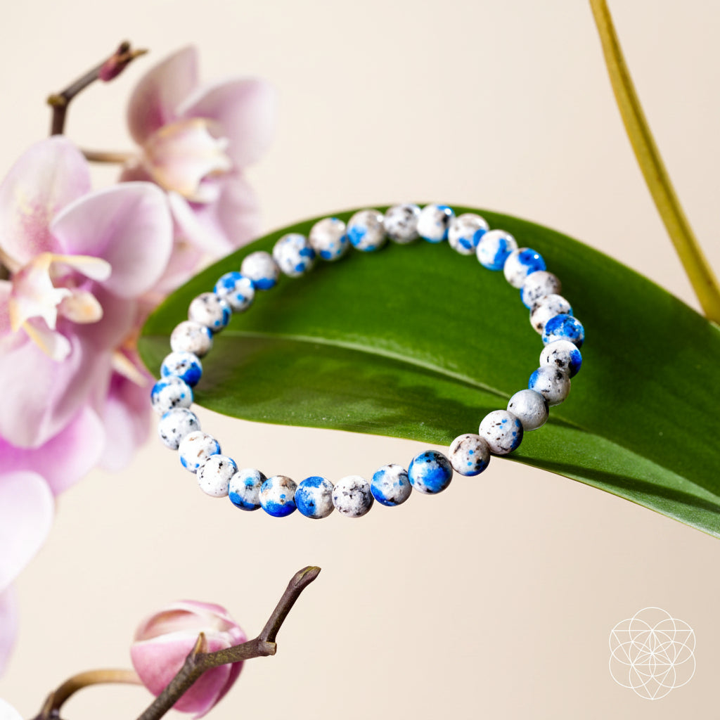 Beaded bracelet with blue and white pattern on a pink background with flowers and leaves