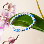 Beaded bracelet with blue and white pattern on a pink background with flowers and leaves