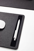 White pen on a black desk pad 