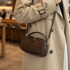 Person wearing a brown leather bag with a blurred store interior in the background