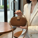 Person holding a brown suede handbag with a wooden table in the background