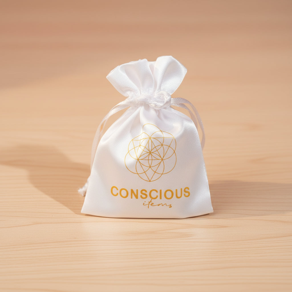 Colorful beaded bracelet on a teal box with 'Conscious' branding, flowers, and a bag in the background.