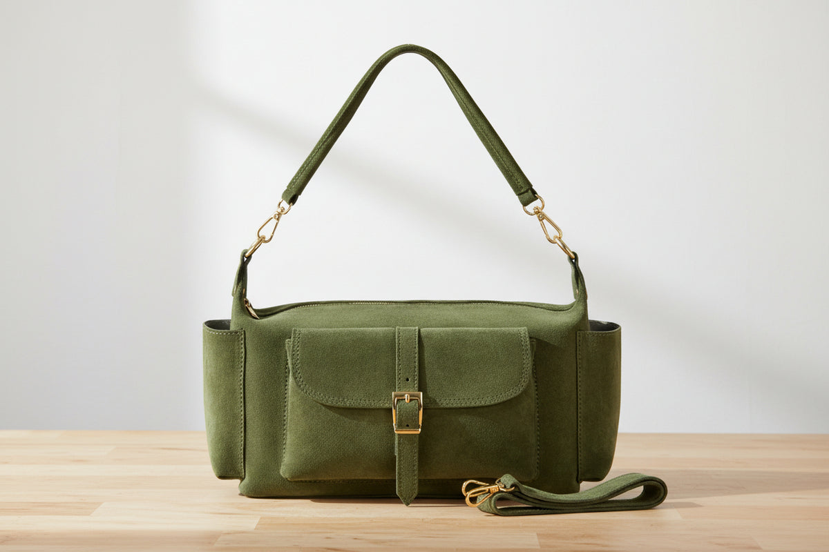 Green handbag with a strap on a wooden surface and light gray background