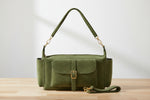 Green handbag with a strap on a wooden surface and light gray background