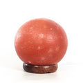 Himalayan Salt Rock sphere on a wooden stand against a white background