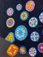 Colorful beaded patches on a dark fabric background