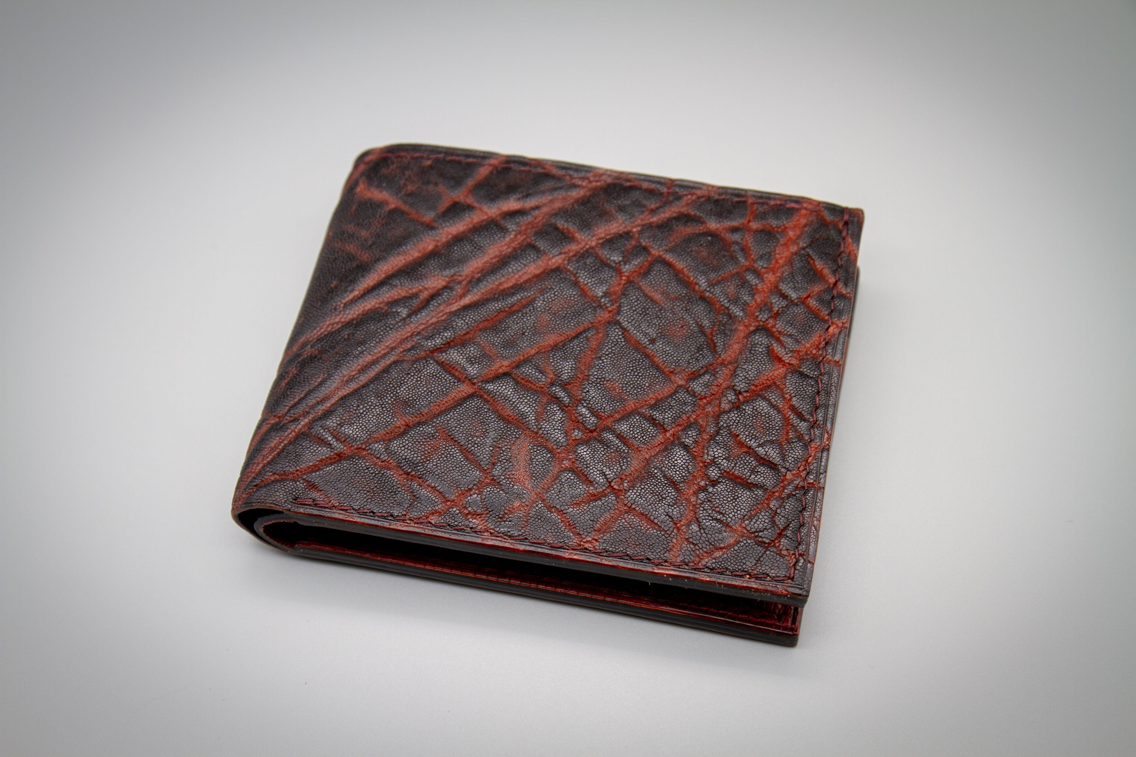 Brown leather wallet with crisscross pattern on a gray background