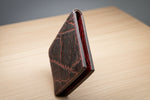 Brown leather wallet with red interior on a wooden surface