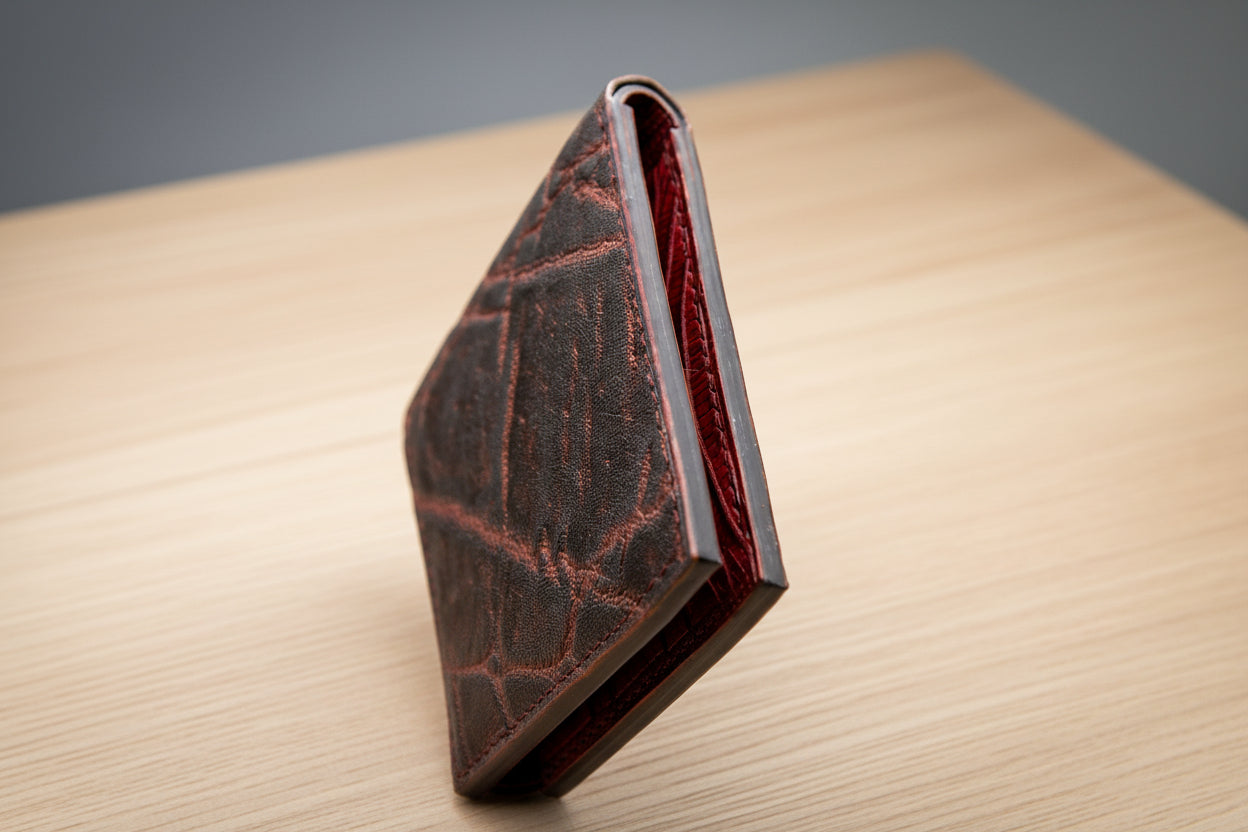 Brown leather wallet with red interior on a wooden surface