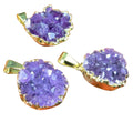 Three purple geode-style pendants with gold accents on a wooden surface