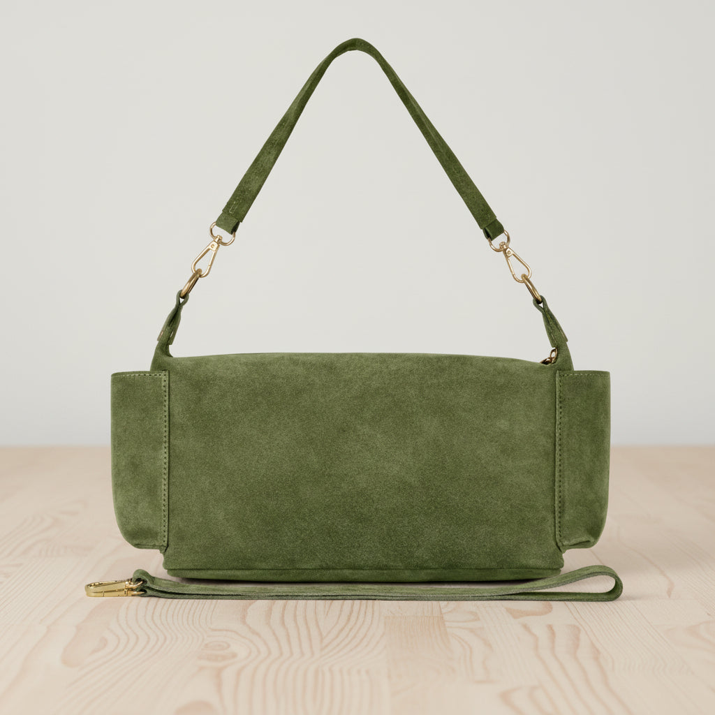 Green suede handbag with a strap on a light gray background