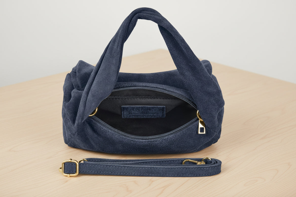 Blue handbag with gold accents on a light gray background