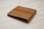 Brown leather wallet on a light wooden surface