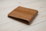 Brown leather wallet on a light wooden surface